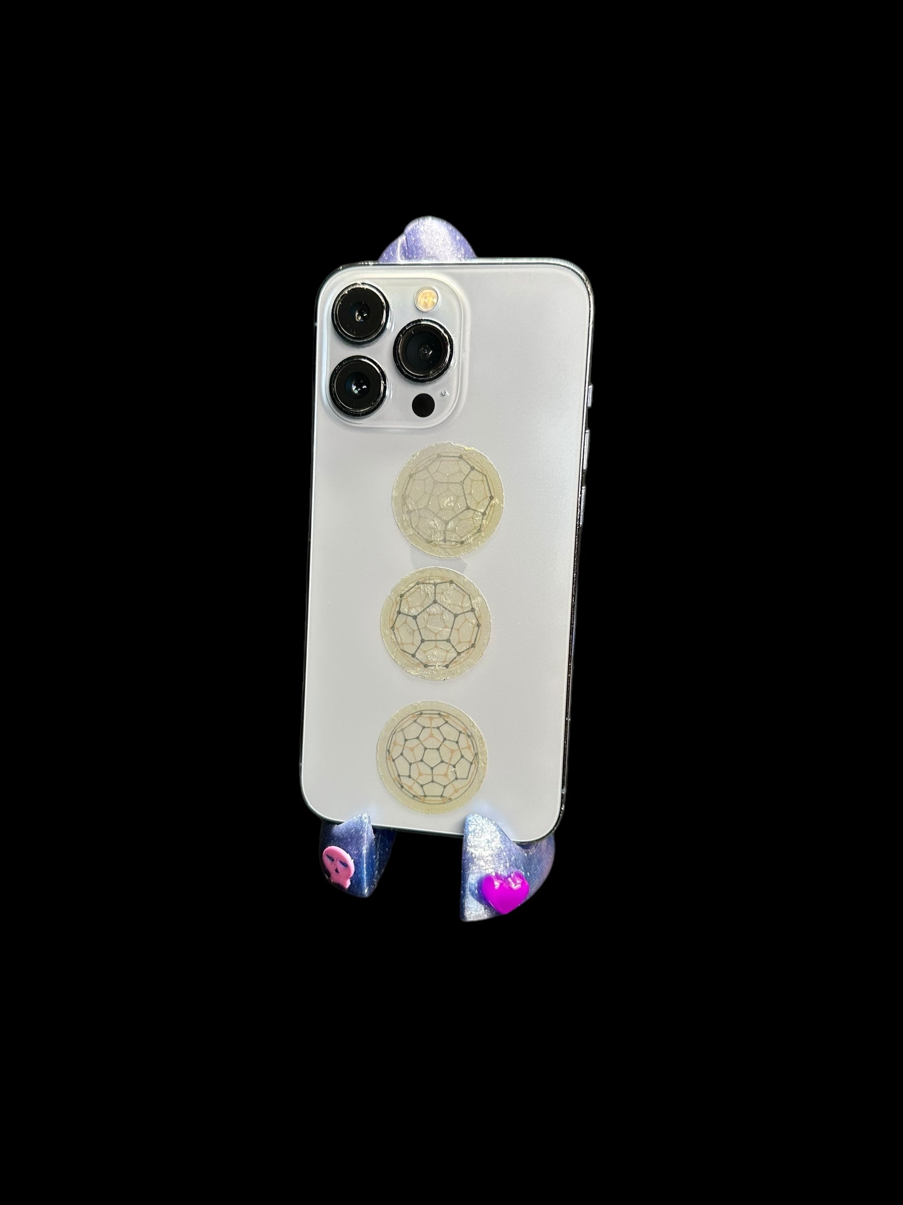 3D-printed phone holder in cosmic blue with pink heart studs, side view holding a phone.
