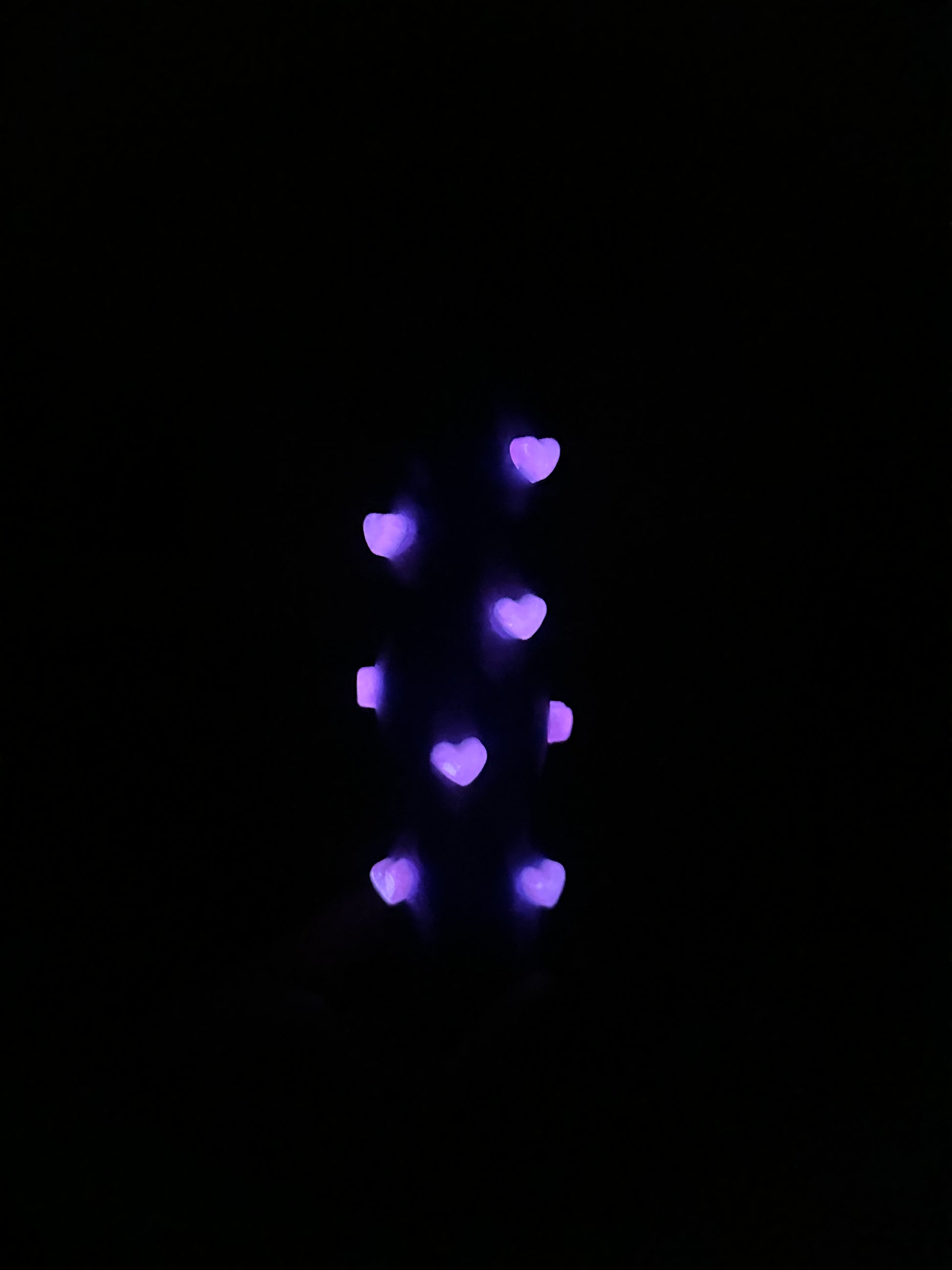 3D-printed phone holder in cosmic blue with pink heart studs, side view holding a phone.